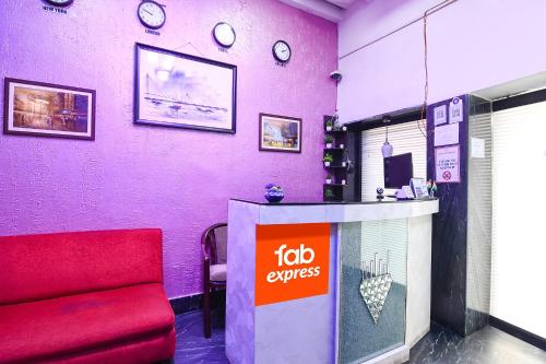 um quarto com um sofá vermelho e relógios na parede em FabExpress New Diamond em Calcutá