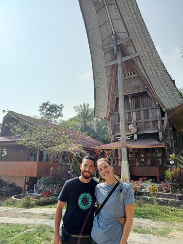 a man and a woman standing in front of a building at NUANSA HOMESTAY Authentic&Hospitality in Rantepao