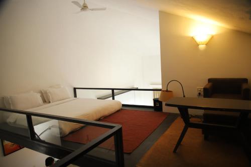 a bedroom with a bed and a table and a chair at Casabela Boutique Hotel in Porvorim