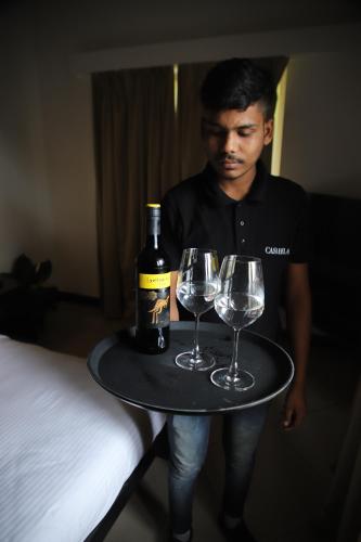 a man holding a tray with a bottle of wine and glasses at Casabela Boutique Hotel in Porvorim
