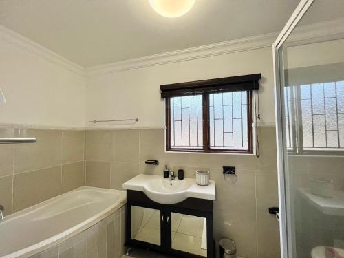 a white bathroom with a sink and a bath tub at Forest View Villa in New Germany
