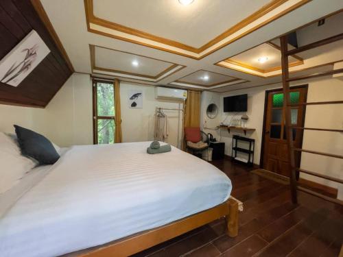 1 dormitorio con 1 cama blanca grande y escritorio en ้hilly phitsano resort, 