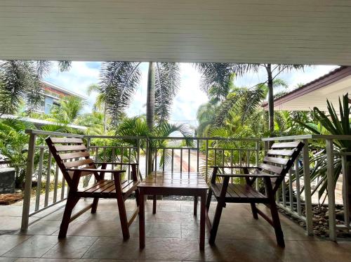 two chairs and a table on a balcony with palm trees at Tan Residence in Ko Lanta