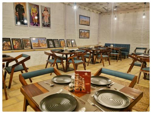 ein Restaurant mit Holztischen und -stühlen und Bildern an der Wand in der Unterkunft Hotel Ajanta Haveli in Jaisalmer