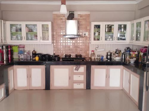 大吉嶺的住宿－Pinewood Homestay，厨房配有白色橱柜和黑色台面