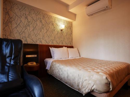 a hotel room with a bed and a chair at GRG Hotel Naha Higashimachi in Naha