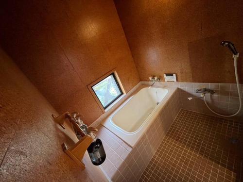 a bathroom with a bath tub and a window at Vineyard Vista Yamanashi in Enzan