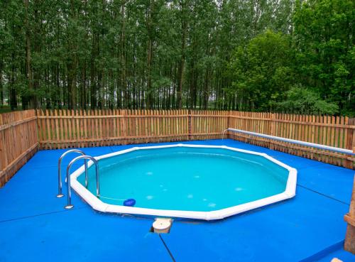 a swimming pool in a backyard with a wooden fence at Béke Tanya Hongarije in Nyársapát