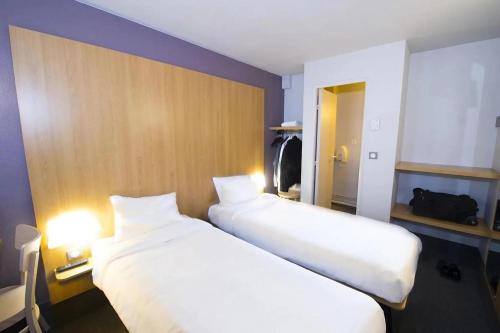 two beds in a hotel room with two white beds at Kyriad Direct Poitiers - Gare du Futuroscope in Chasseneuil-du-Poitou