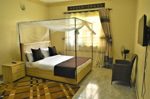 um quarto com uma cama de dossel e uma cadeira em Beautiful home opposite Speke Resort Munyonyo near Lake Victoria em Kampala