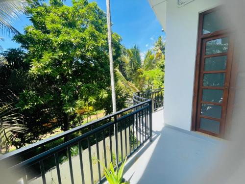 a balcony of a house with a window and trees at White House Hotel Mirissa in Mirissa