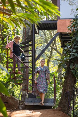 two women walking down a stairs in a forest at Eterno Camellia & Elettaria Resort with Pool in Munnar