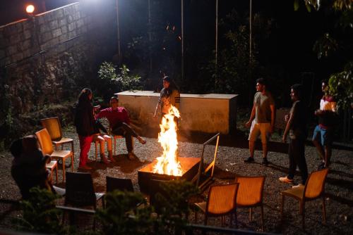 a group of people sitting around a fire at Eterno Camellia & Elettaria Resort with Pool in Munnar