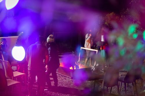 a group of people standing around a fire at night at Eterno Camellia & Elettaria Resort with Pool in Munnar