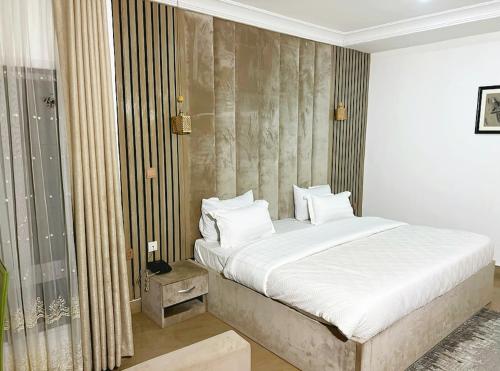 a bedroom with a large bed with white sheets and pillows at Grey Residence in Abuja