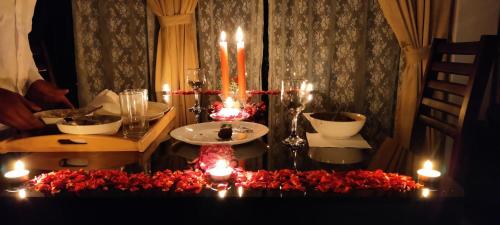 a table with candles and red flowers on it at Paadi Holidays Idukki in Idukki