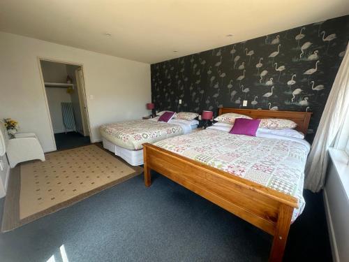 a bedroom with two beds and a wall with birds on it at Sunny House with 5 Bedrooms(near airport) in Christchurch
