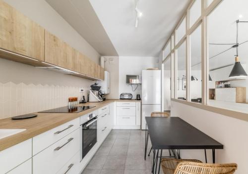 a kitchen with white cabinets and a black table at Élégant T3 au Panier Vieux Port avec Terrasse Privée et Parking in Marseille