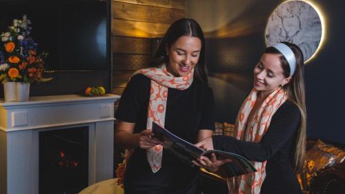 two women standing next to each other in a room with a fireplace at Hotel Golden Circle Suites in Rovaniemi