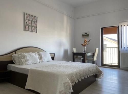 a bedroom with a bed and a table with a window at Mares Rentals Residence Magurele in Măgurele