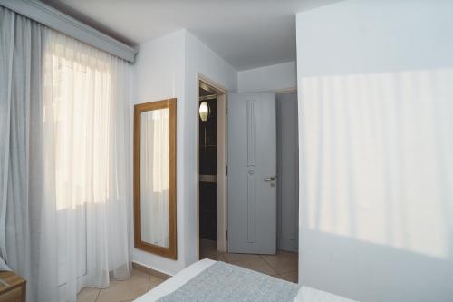 a white bedroom with a mirror and a bed at Zeus Village Resort - Adults Only in Kato Daratso