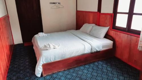 a bedroom with a bed with white sheets and a window at Rainbow guest House in Ban Pho Touane