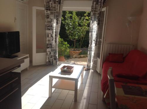 a living room with a red couch and a table at Rez de Villa Pébrier in Fréjus