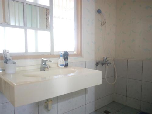 uma casa de banho com um lavatório, uma janela e um chuveiro em Joel's Garden 悠爾庭園古厝民宿 em Baihe