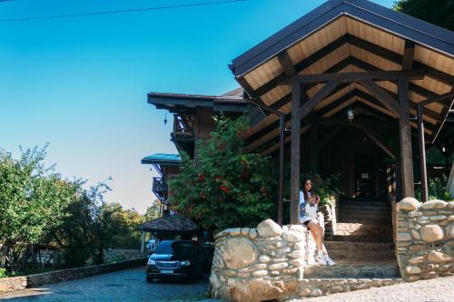 a woman sitting on the steps of a house at BRB Park Hotel in Vizhenka
