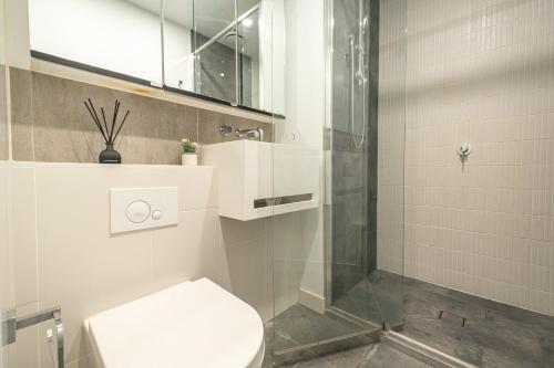 La salle de bains est pourvue de toilettes et d'une douche en verre. dans l'établissement Spectacular High Level 2br Cbdpoolgymwi-fi, à Melbourne