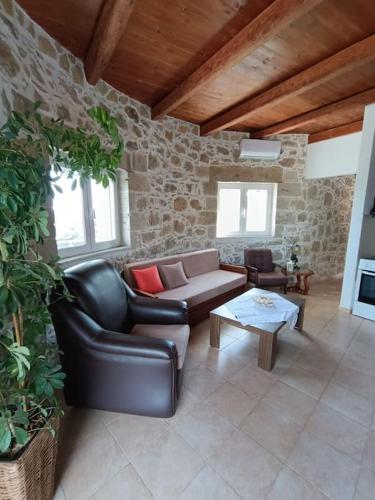 a living room with a leather couch and a table at Rokka Pyrgos Amazing View - Maistros in Rókka