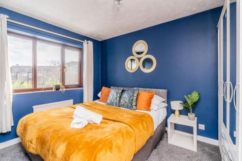 a blue bedroom with a large bed with orange sheets at Central MK Comfy FAMILY CONTRACTOR 3B house Free Parking managed by Chique Properties Ltd in Shenley Lodge