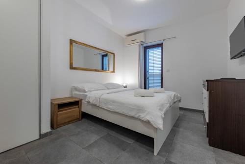 a white bedroom with a bed and a mirror at Aparthotel Plat in Kožino