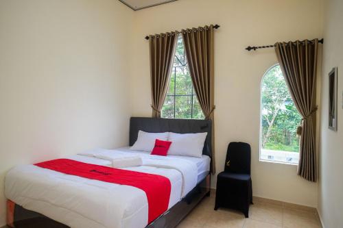una camera da letto con un letto con una coperta rossa sopra di RedDoorz near Terminal Bus Purwokerto a Banyumas