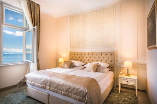 a bedroom with a large bed with a large window at Hotel Palace Bellevue - Liburnia in Opatija