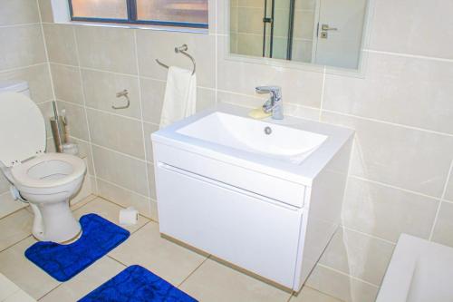 a bathroom with a white sink and a toilet at The Blyde Crystal Lagoon in Pretoria