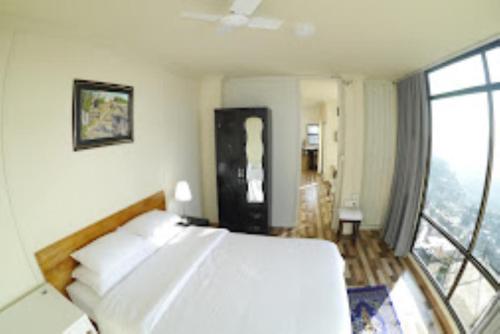 a bedroom with a white bed and a large window at Aizawl Guest House, Aizwal in Āīzawl