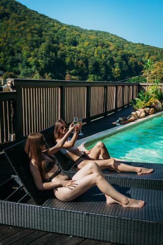 two women laying on a deck next to a swimming pool at BRB Park Hotel in Vizhenka