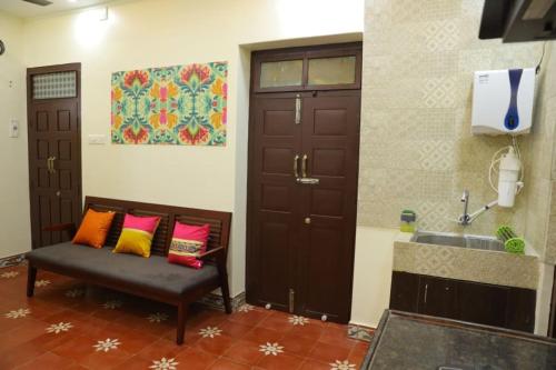 a room with a door and a bench with colorful pillows at Heritage home with 3 bed/3 bath with kitchen in a residential neighborhood. in Madurai