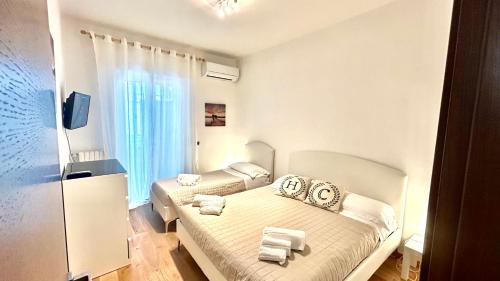 a bedroom with two beds with white sheets and towels at HomeClass in Bari