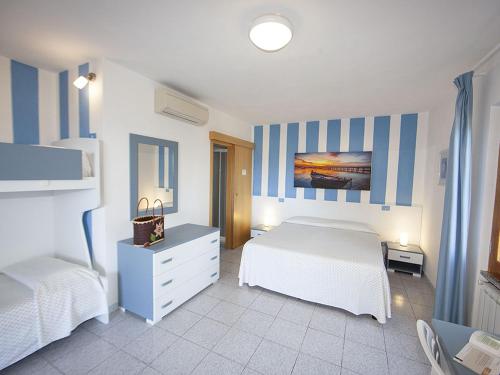 a bedroom with two beds and blue and white stripes at Hotel Aurora in Chiessi