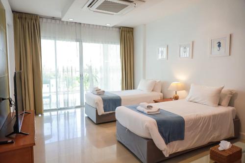 a hotel room with two beds and a television at Royal Beach View in Pattaya South