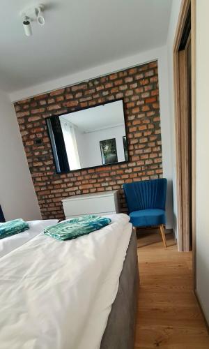 a bedroom with a bed and a mirror on a brick wall at Apartamenty Dębowa 3 in Polanica-Zdrój