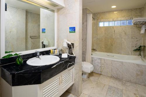bagno con lavandino, vasca e servizi igienici di Court Wing Hotel Sukhumvit Bangkok a Bangkok
