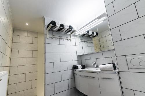 un bagno piastrellato bianco con lavandino e specchio di Vakantiewoningen De Jud a Maasmechelen