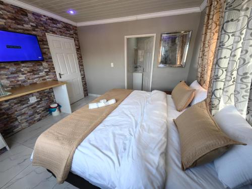a bedroom with a large bed and a tv at Essential Lodge23 in Cape Town