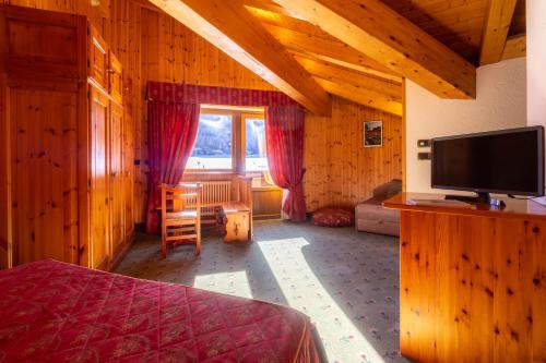 a bedroom with a bed and a flat screen tv at Hotel Bouton D'Or - Cogne in Cogne