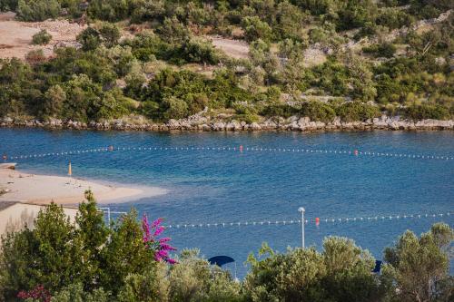 a body of water with a beach and trees at Apartments Villa Monique in Rogoznica