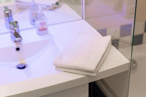 - un lavabo dans la salle de bains avec 2 serviettes sur un comptoir dans l'établissement 7 min walk to La Défense modern flat in aparthotel, à Courbevoie