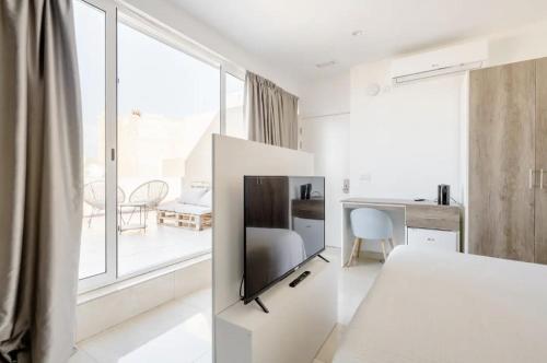 Habitación blanca con TV en la pared en Hammock Vibes Town House en Sliema